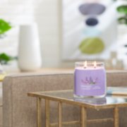 lilac blossoms signature medium jar candle lit on side table image number 4