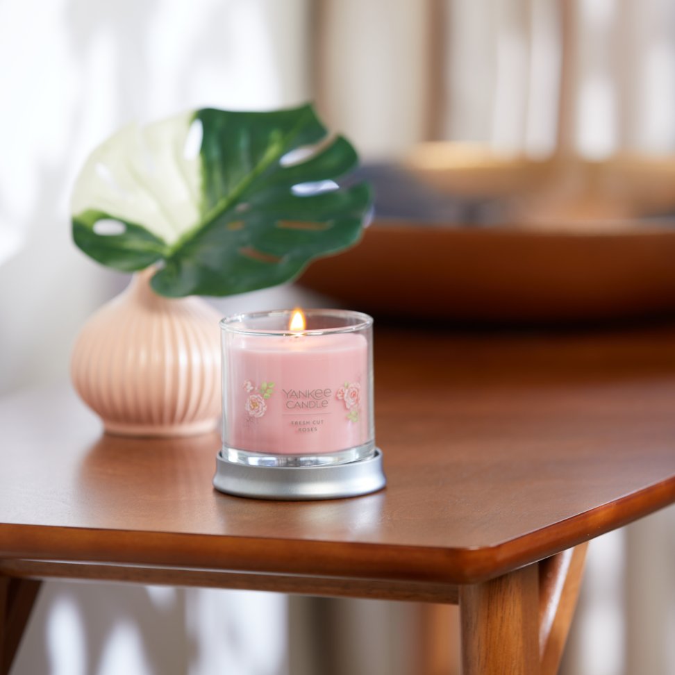 fresh cut roses signature small tumbler candle lit on side table