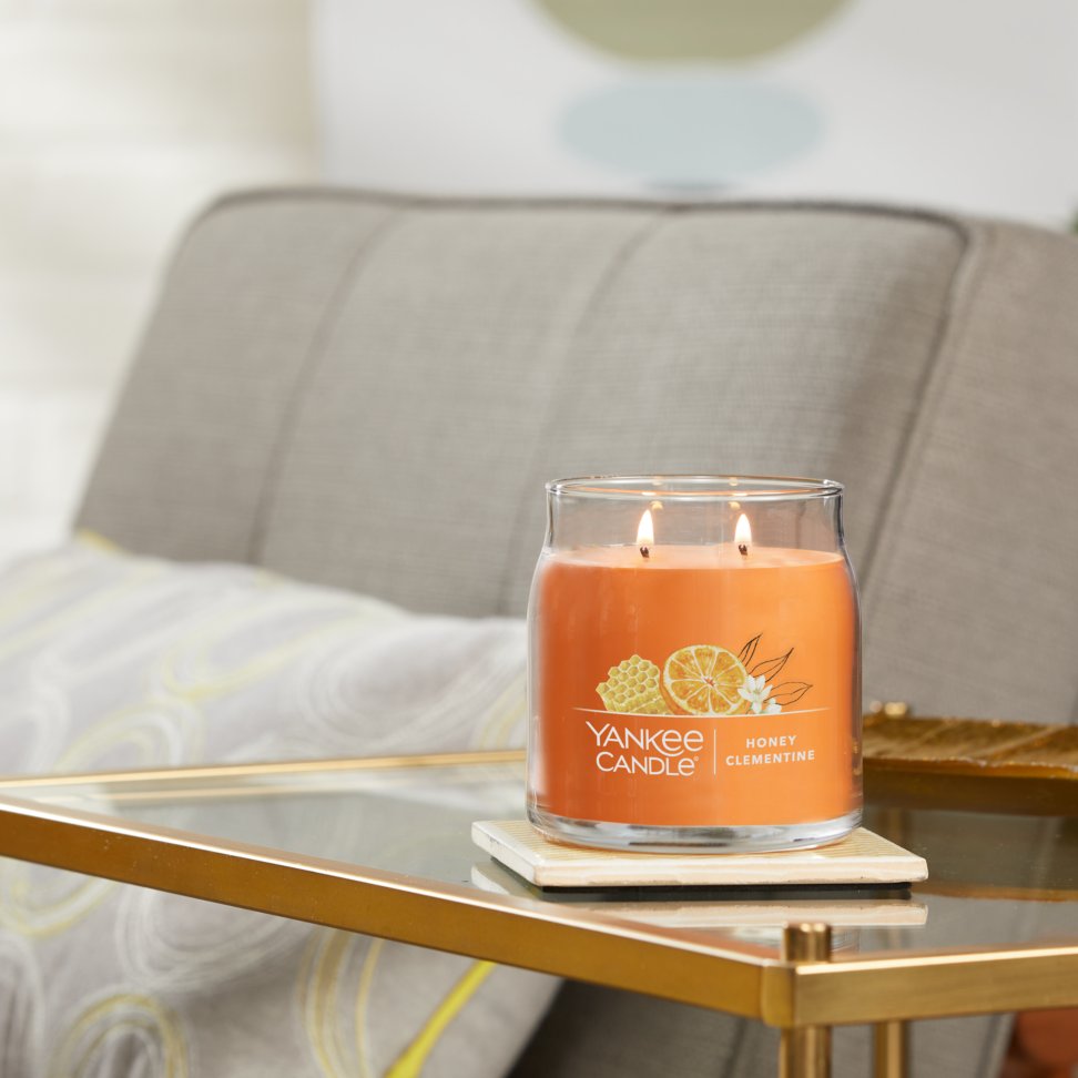 honey clementine signature medium jar candle lit on side table