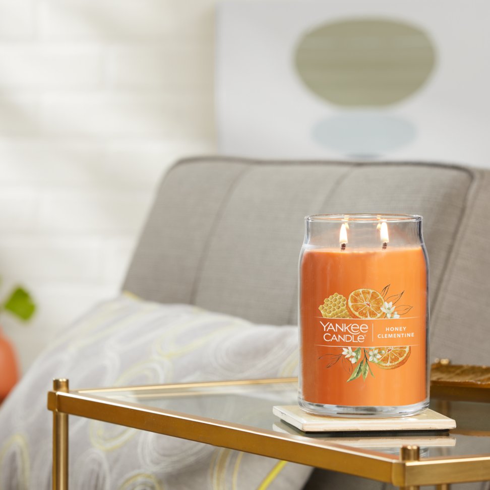 honey clementine signature large jar candle lit on side table with coaster