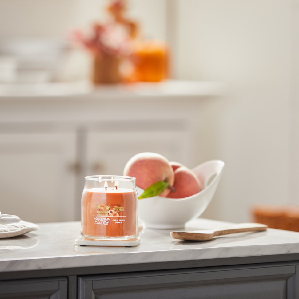 farm fresh peach signature medium jar candle on kitchen counter