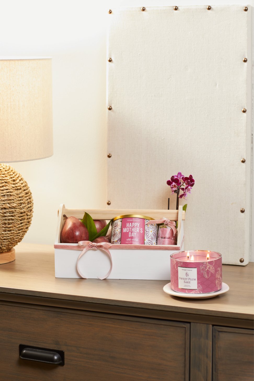 sweet plum sake three wick candle on dresser beside gift box featuring wild orchid happy mothers day three wick candle