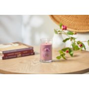 lit wild orchid signature medium pillar candle on wooden table next to books and a flower vase image number 4