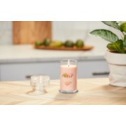 lit tangerine and vanilla signature medium pillar candle on wooden counter image number 4