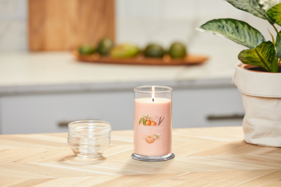 lit tangerine and vanilla signature medium pillar candle on wooden counter