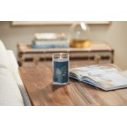 lit bayside cedar signature medium pillar candle on wooden table next to a book image number 4