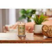 lit sun and sand signature medium pillar candle on wooden table next to a potted plant and basket image number 3