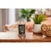 lit silver sage and pine signature medium pillar candle on wooden table next to a potted plant and basket image number 3