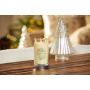 lit christmas cookie signature medium pillar candle on wooden table next to a white and silver glitter tree image number 4