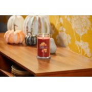 lit apple pumpkin signature medium pillar candle on wooden table next to pumpkins and yellow floral wallpaper image number 4