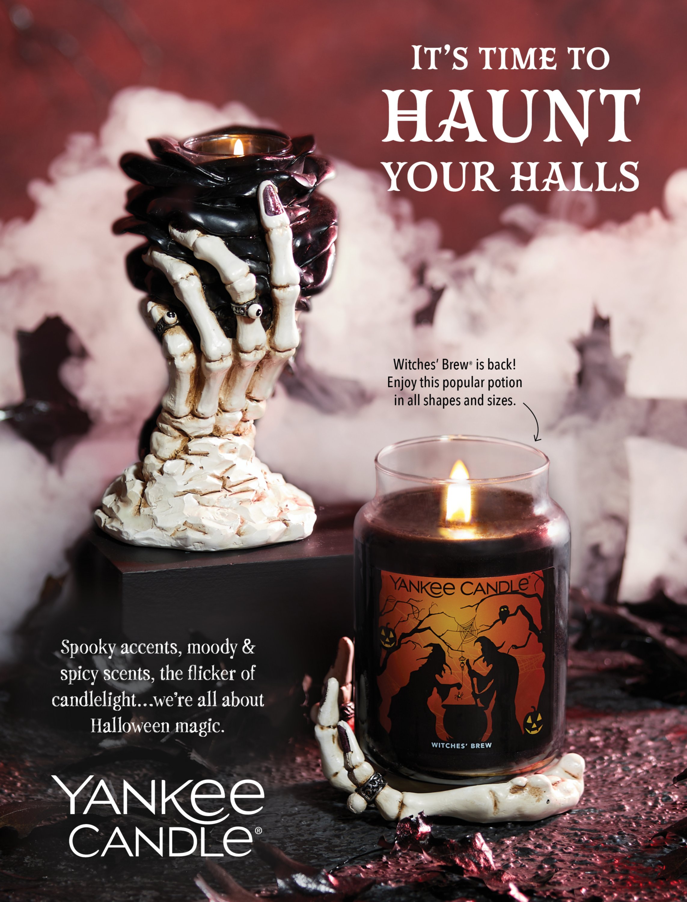 a photo of a witches' brew® original large jar candle with a limited edition label on a phantasmagoria hand jar candle holder next to a phantasmagoria black rose votive and tea light candle holder