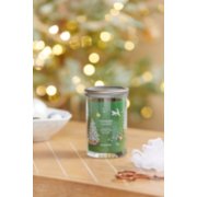 shimmering christmas tree signature large tumbler candle on a table next to a white bowl with ornaments image number 3