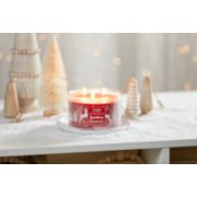 sparkling cinnamon three wick candle on white plate on snowy surface with rustic wood and brush christmas trees image number 3