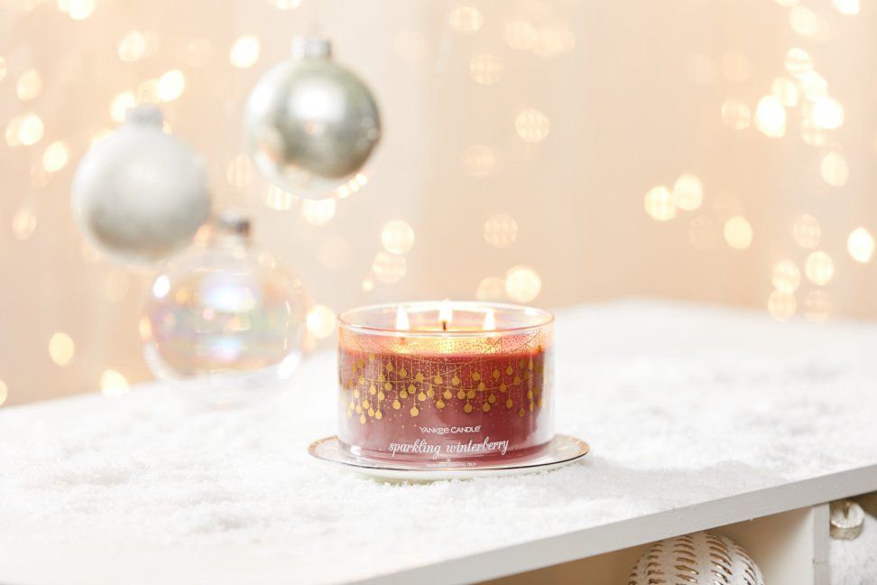 sparkling winterberry three wick candle on plate on snowy surface with white ornaments and gold sparkles
