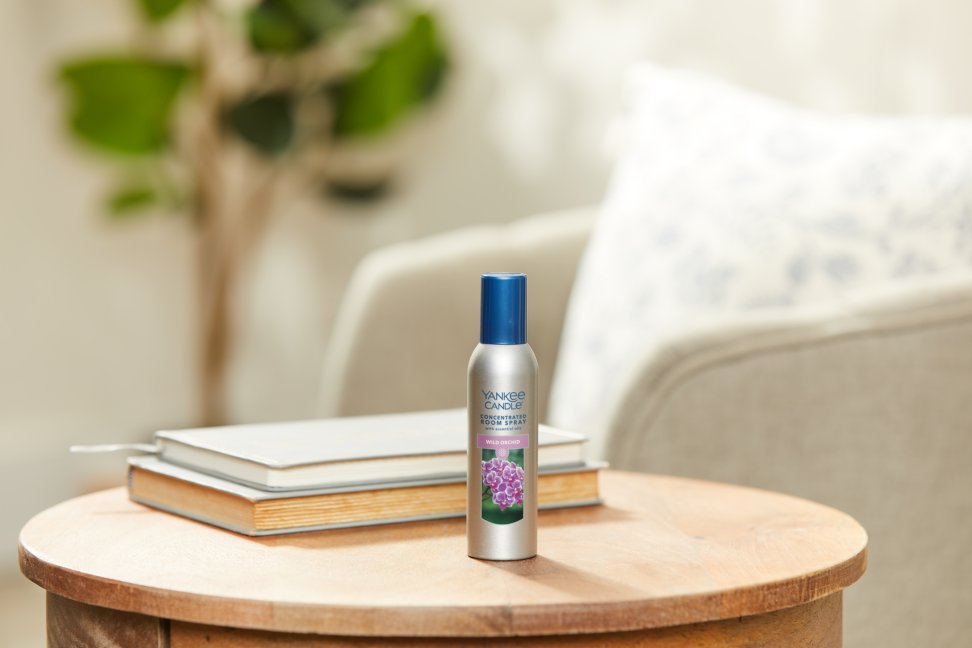 wild orchid concentrated room spray on a wood table next to two books