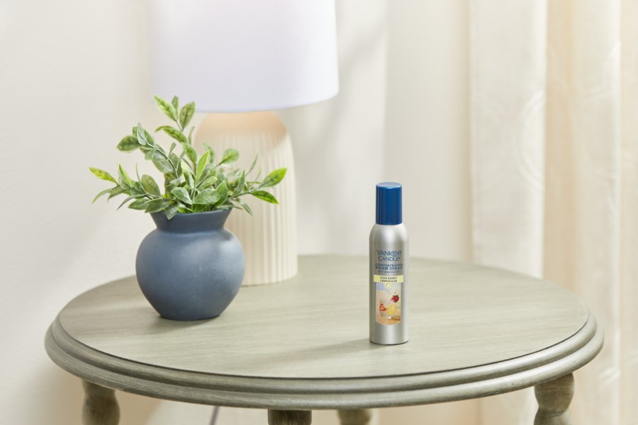 iced berry lemonade concentrated room spray on a wood table next to a plant and a lamp
