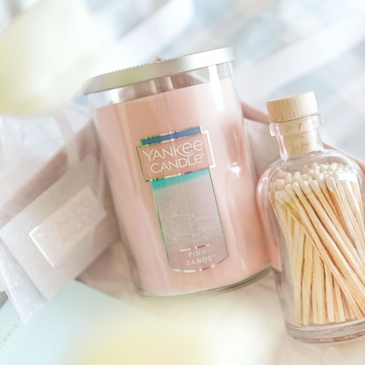 pink sands signature large tumbler candle next to glass bottle holding unlit matches