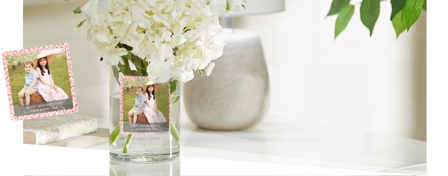white flowers in a glass vase with a personalized photo label on a white table