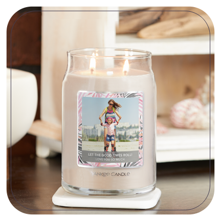 a cream-colored signature large jar candle with a personalized photo label of a woman and a young girl with messaging saying let the good times roll and love you so much on a table