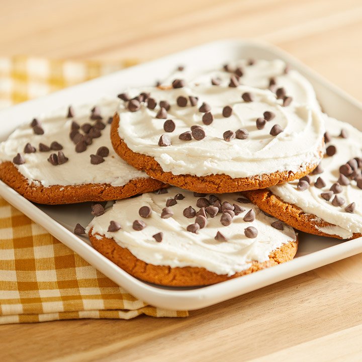 frosted chocolate chip cookies on a tray with a gingham towel