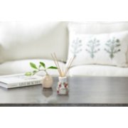 a black table with a book and a plant in a beige vase in front of a white couch with a decorative pillow image number 2
