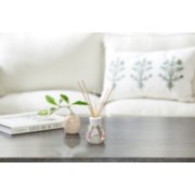 a black table with a book and a plant in a beige vase in front of a white couch with a decorative pillow image number 2