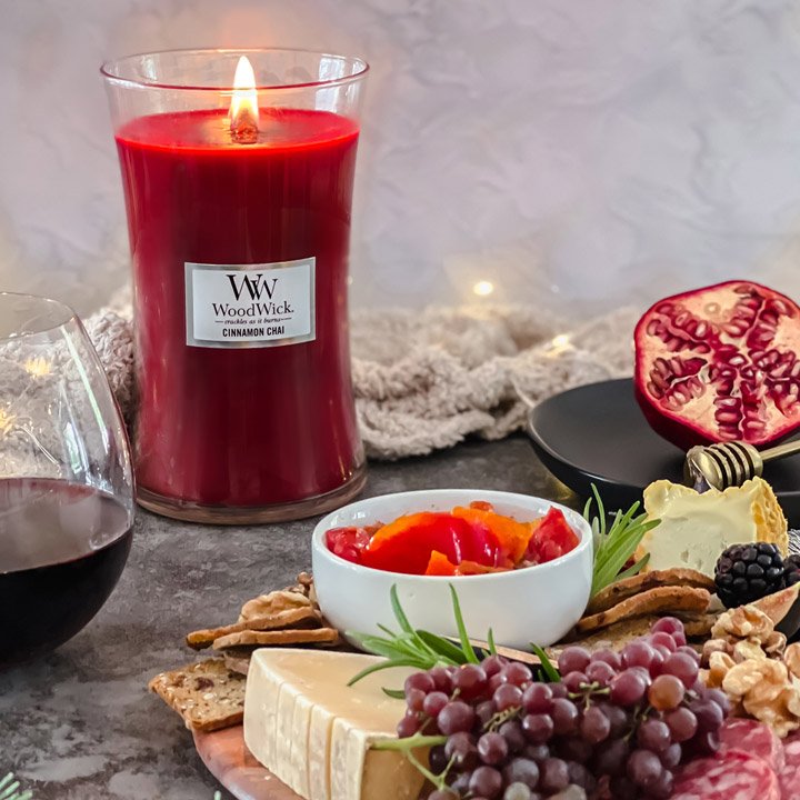 Lit candle on table with glass of wine and food