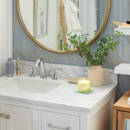 studio candle burning on glass coaster on sink in bathroom