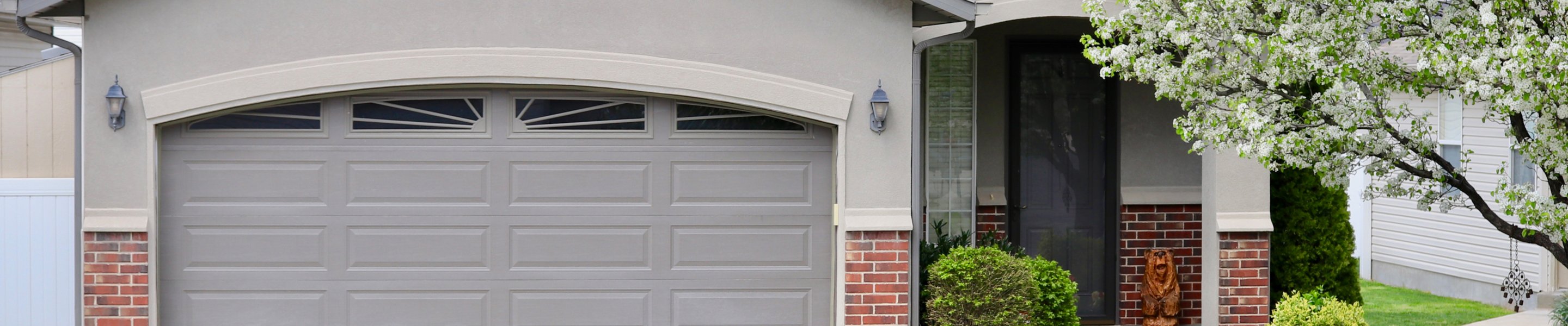 gray garage door and front of house with wood bear sculpture